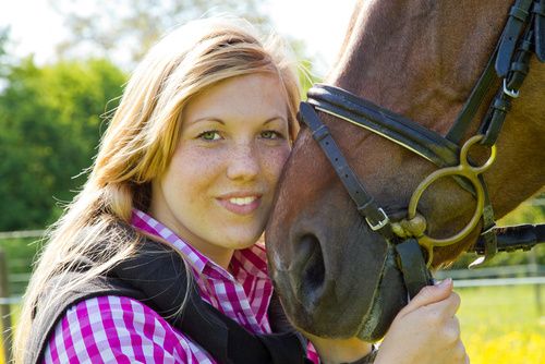 Junge blonde Frau schmust mit Pferd