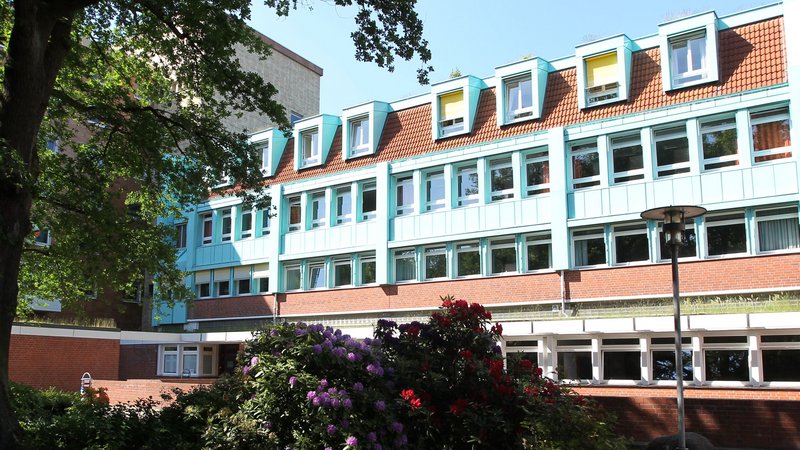 Blick auf die Evangelische Hochschule durch den blühenden Park.