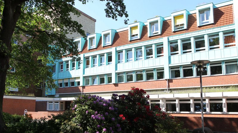 Blick auf die Evangelische Hochschule durch den blühenden Park.