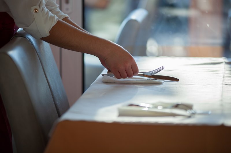 Eine Person deckt einen Tisch in einem Restaurant.