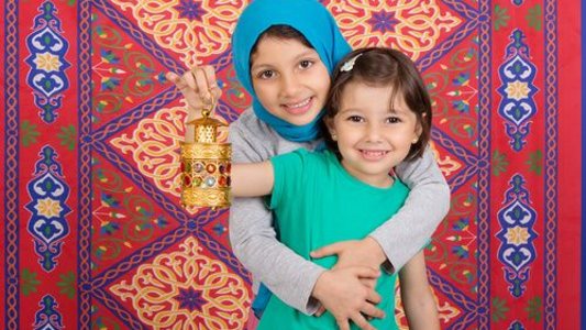 Ein größeres Mädchen umarmt ein kleineres Mädchen vor einem Orientteppich.