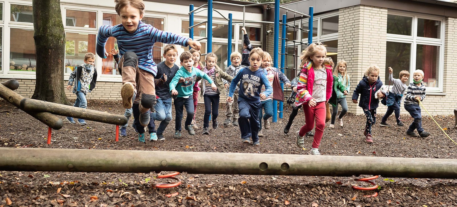 Eine Gruppe von Schulkindern der 1. Klasse toben auf dem Schulhof.