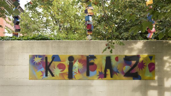 Kunstplakat KiFaz hängt an einer Mauer.