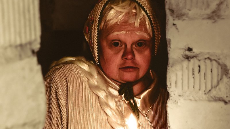 Eine Person leuchtet mit einer Kerze in einen dunklen Raum hinein