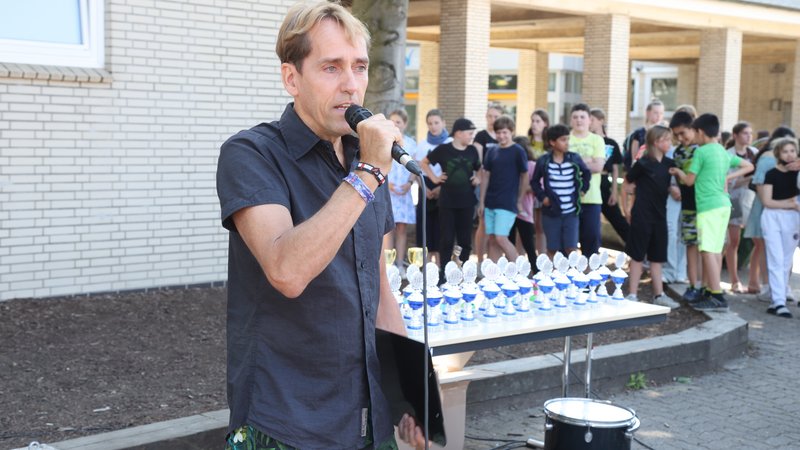 Sportlehrer Till Teuber hält eine kleine Ansprache und ehrt die Klassen, die am Lauf teilgenommen haben.