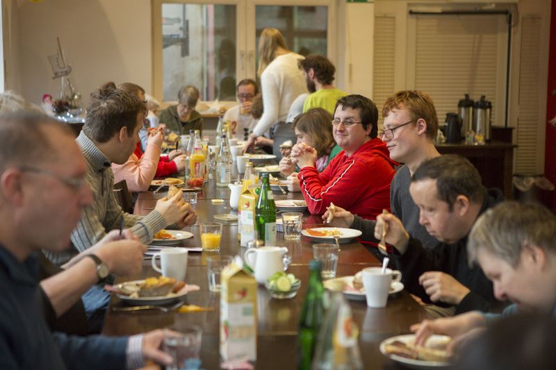 Menschen an einem langen Tisch essen gemeinsam.
