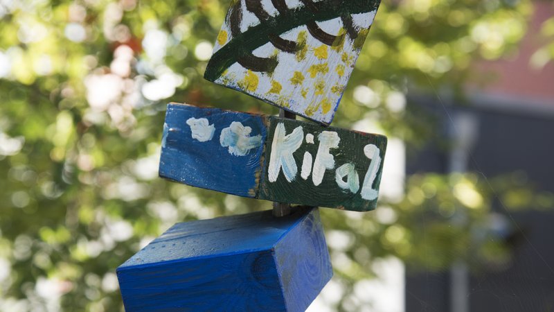 Bemalte Holzklötze in einem Baum mit der Aufschrift KiFaz