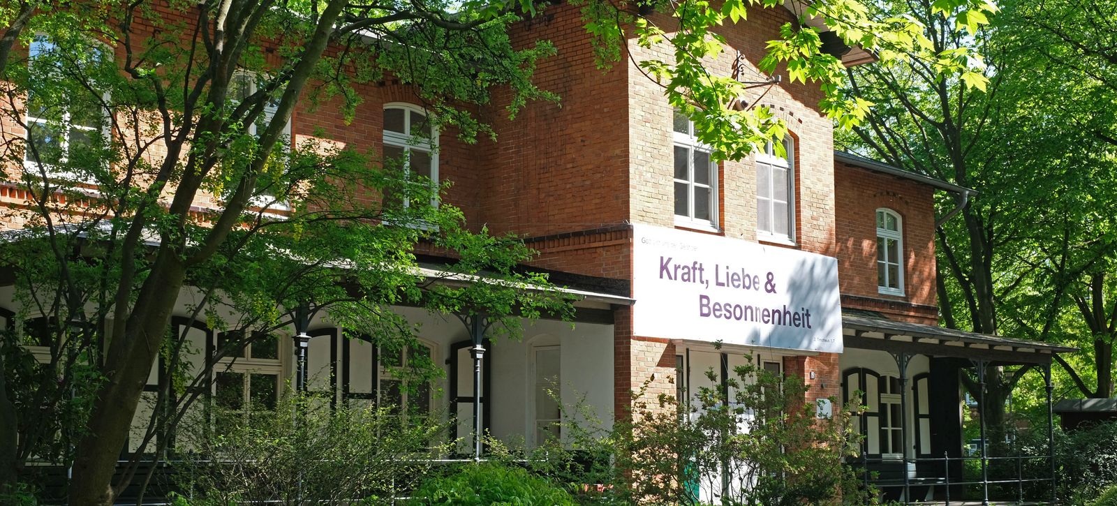 Haus Anker auf dem Stiftungsgelände mit Banner an der Hauswand "Kraft, Liebe & Besonnenheit"