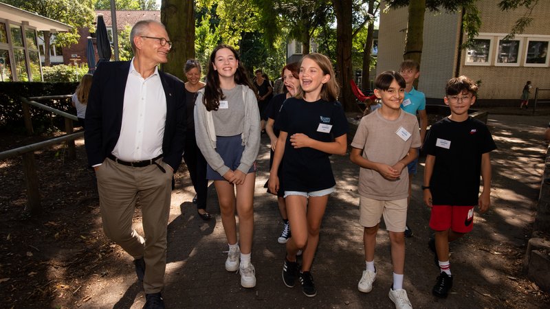 Diakonie-Präsident Ulrich Lilie lässt sich von Schülerinnen und Schülern das Gelände der Wichern-Schule zeigen.