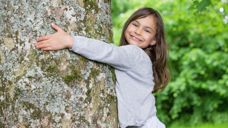 Ein Mädchen umarmt einen Baum.