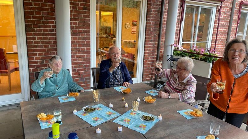 Eine Gruppe Senioren genießt den Abend auf dem Balkon.